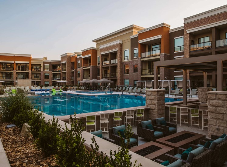 view of outdoor pool and lounge area with chairs surrounded by apartment complex buildings
